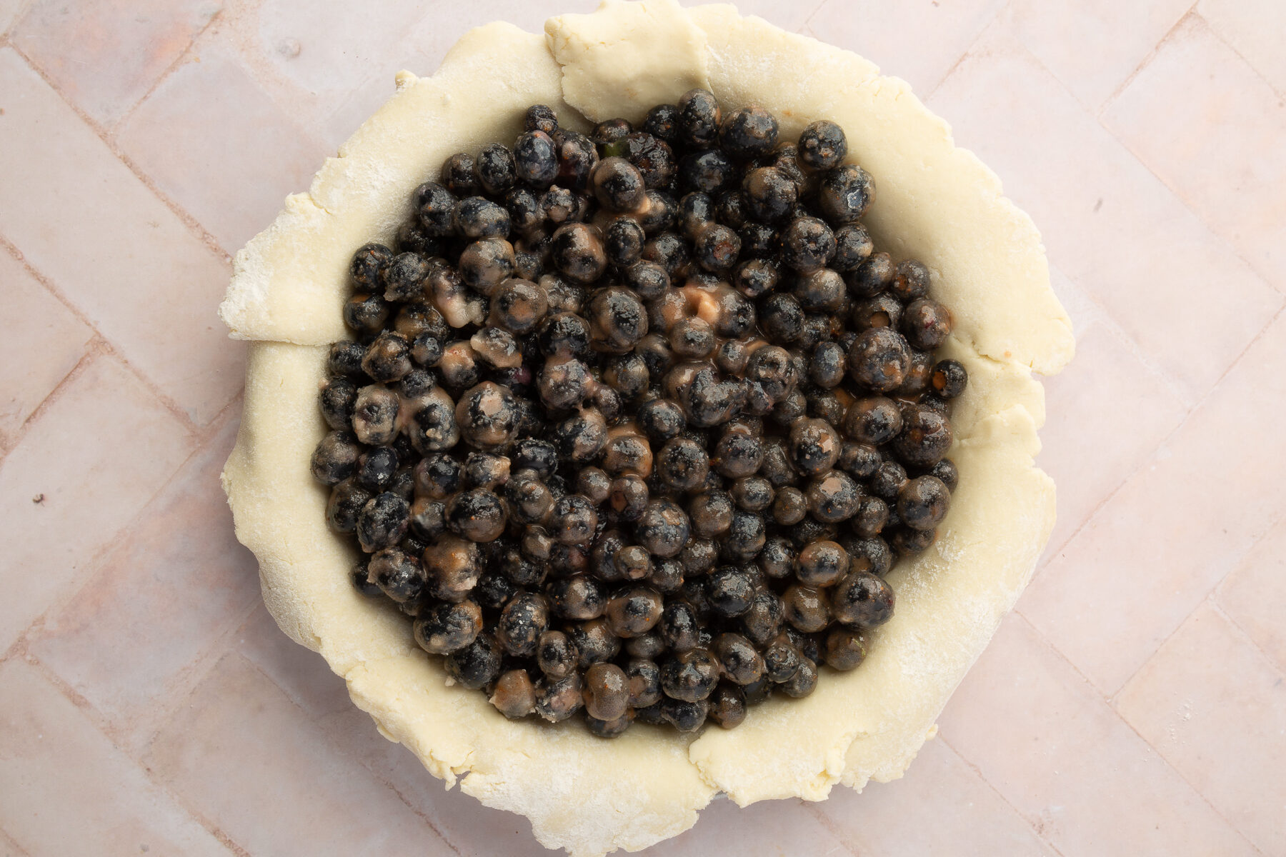 Blueberries mixed with sugar and cinnamon filling a raw gluten-free pie crust, waiting for the lattice top to be added.