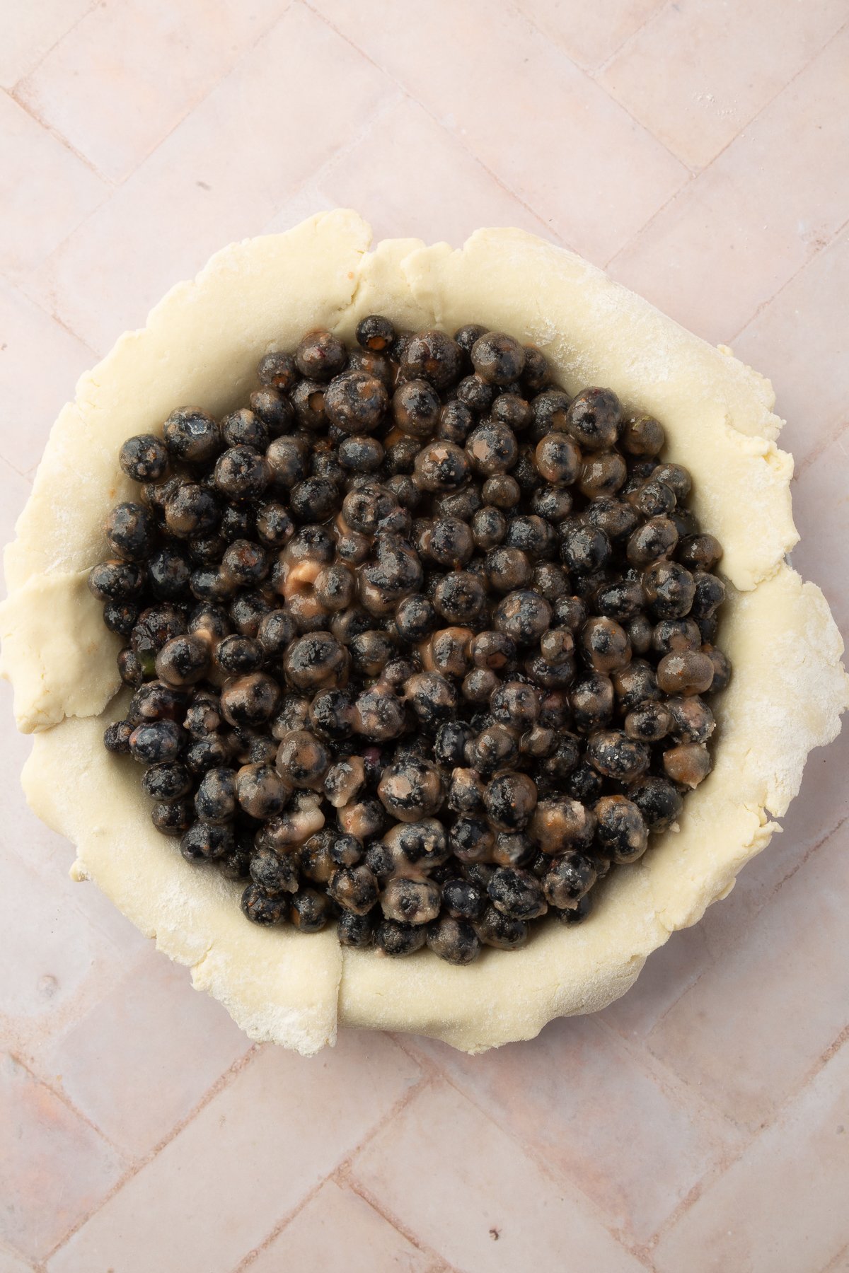 Blueberries mixed with sugar and cinnamon filling a raw gluten-free pie crust, waiting for the lattice top to be added.