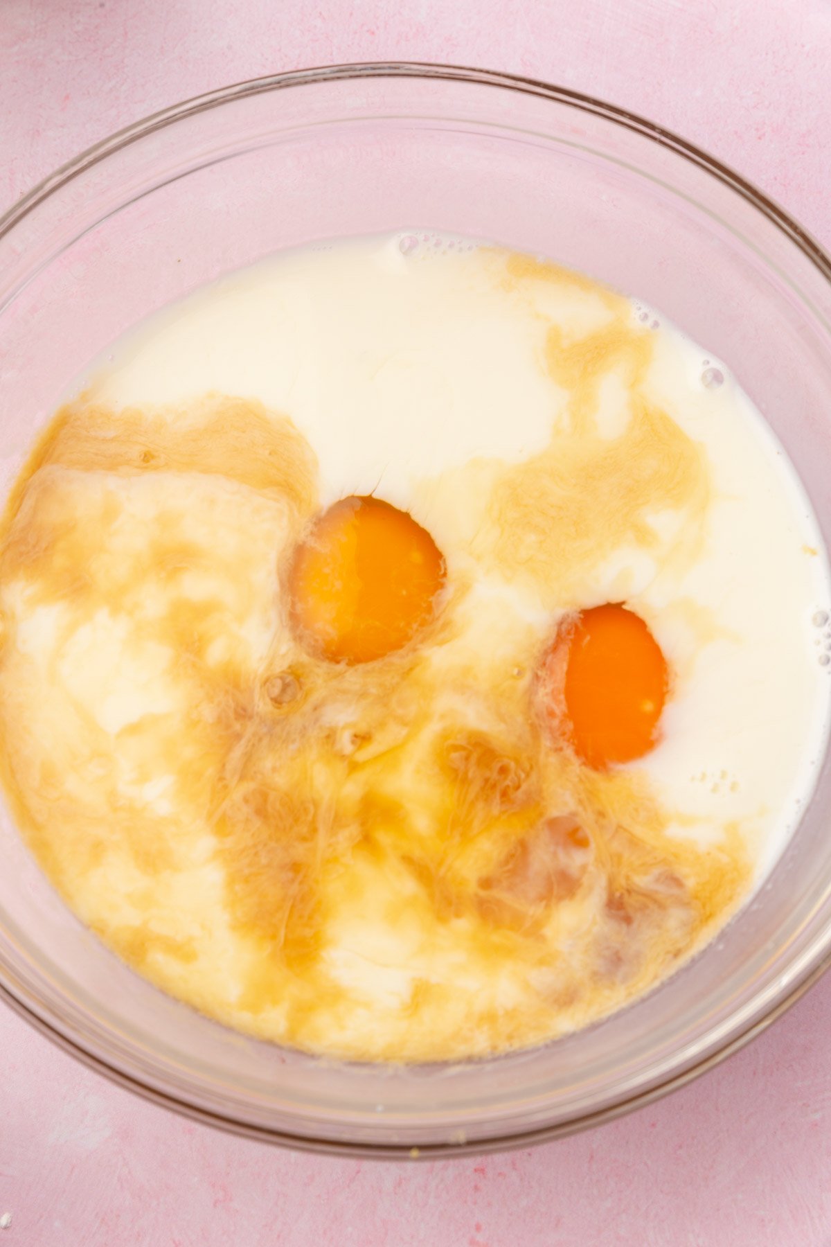 Mixing bowl containing eggs, milk, and vanilla before whisking.
