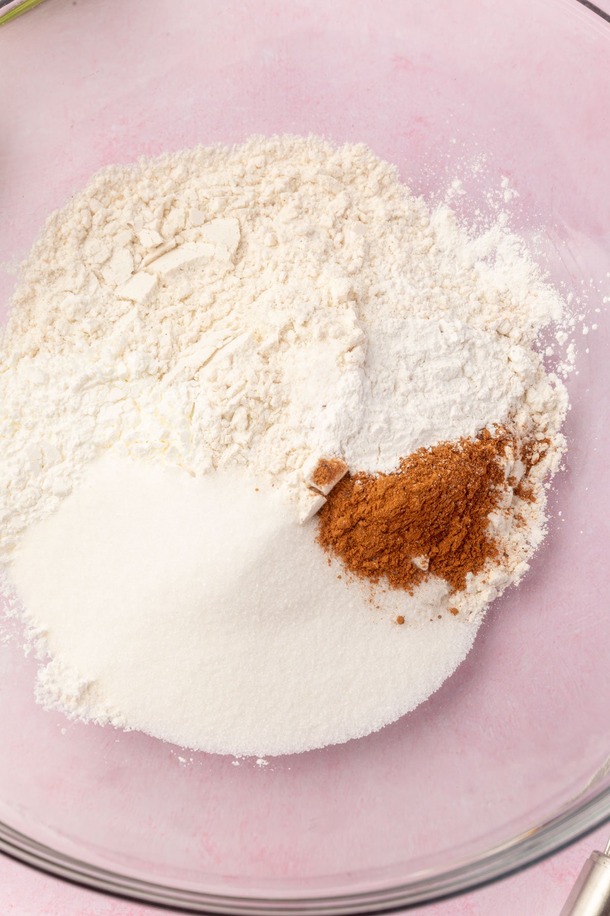 Bowl with dry ingredients for apple fritters, including flour and spices, ready to be mixed.