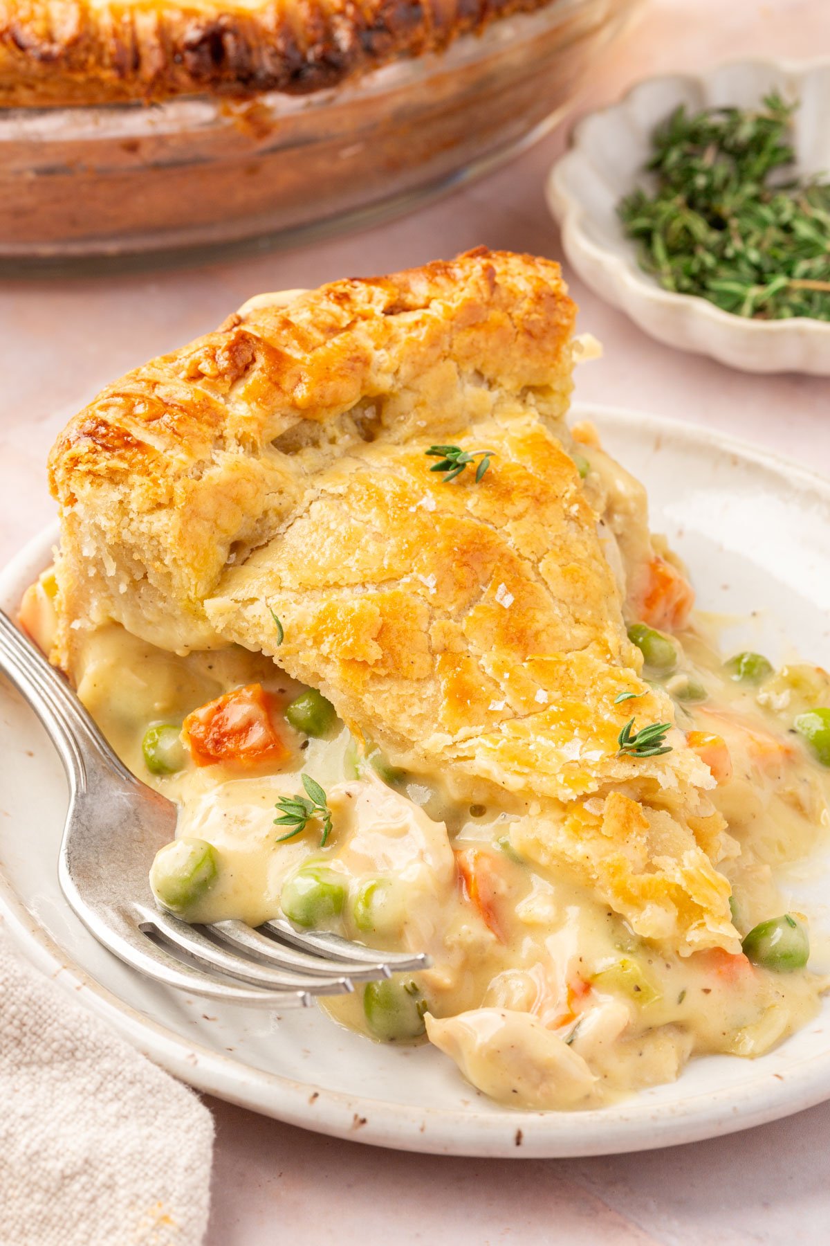 A piece of gluten-free chicken pot pie sitting on a beige plate with a fork next to it.