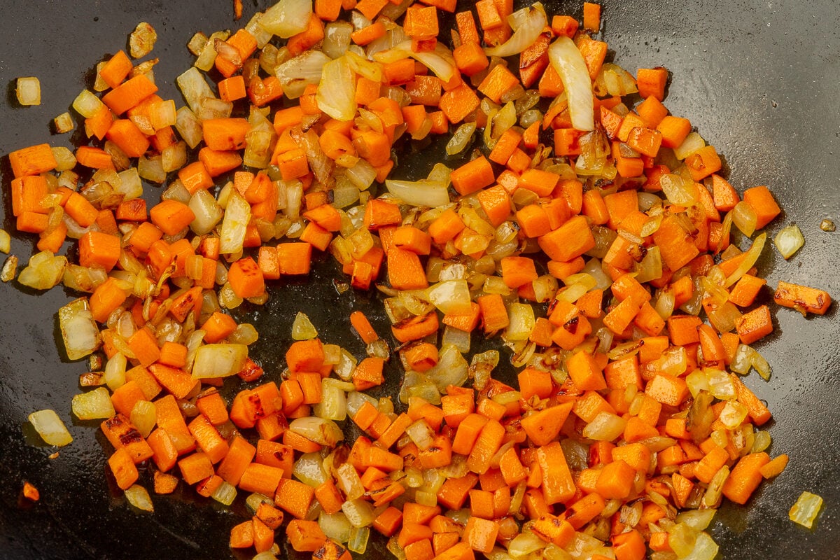 Carrots and onions in large wok mixed together.