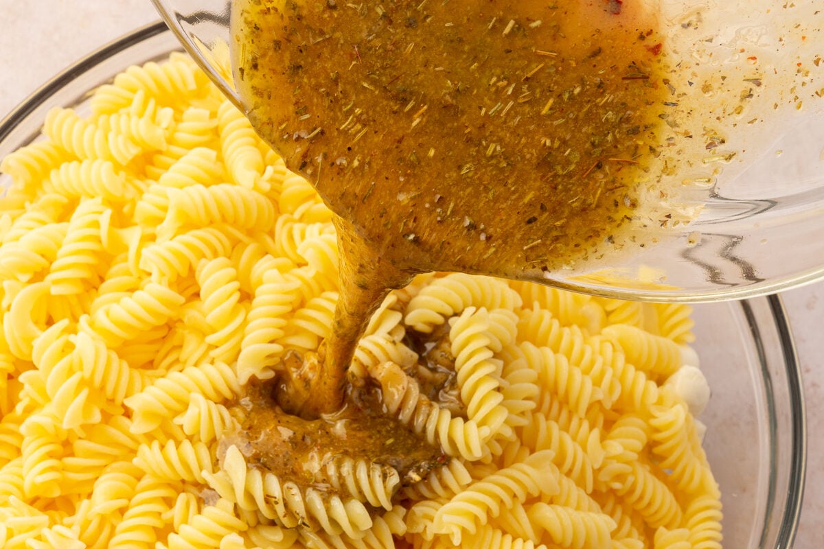 Finished dressing being poured over gluten-free pasta.