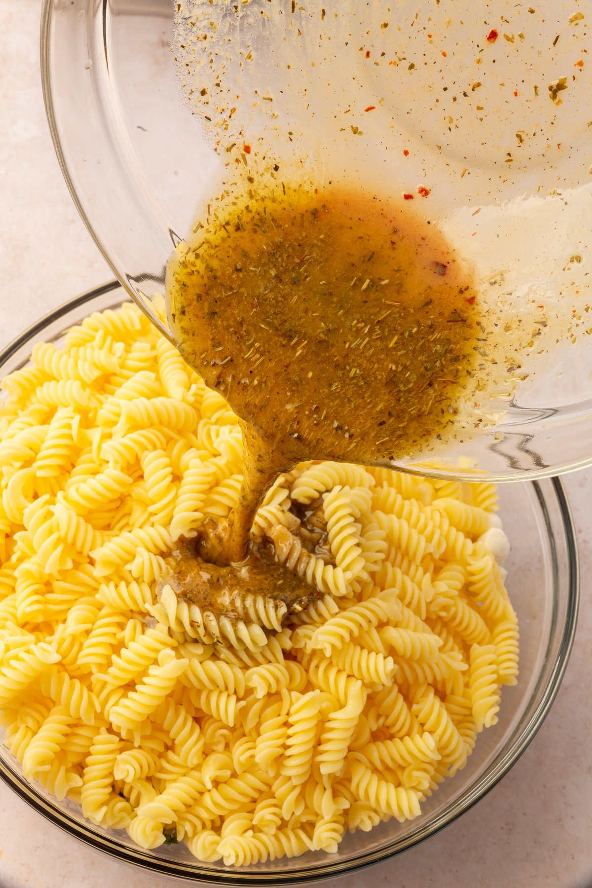 Finished dressing being poured over gluten-free pasta.