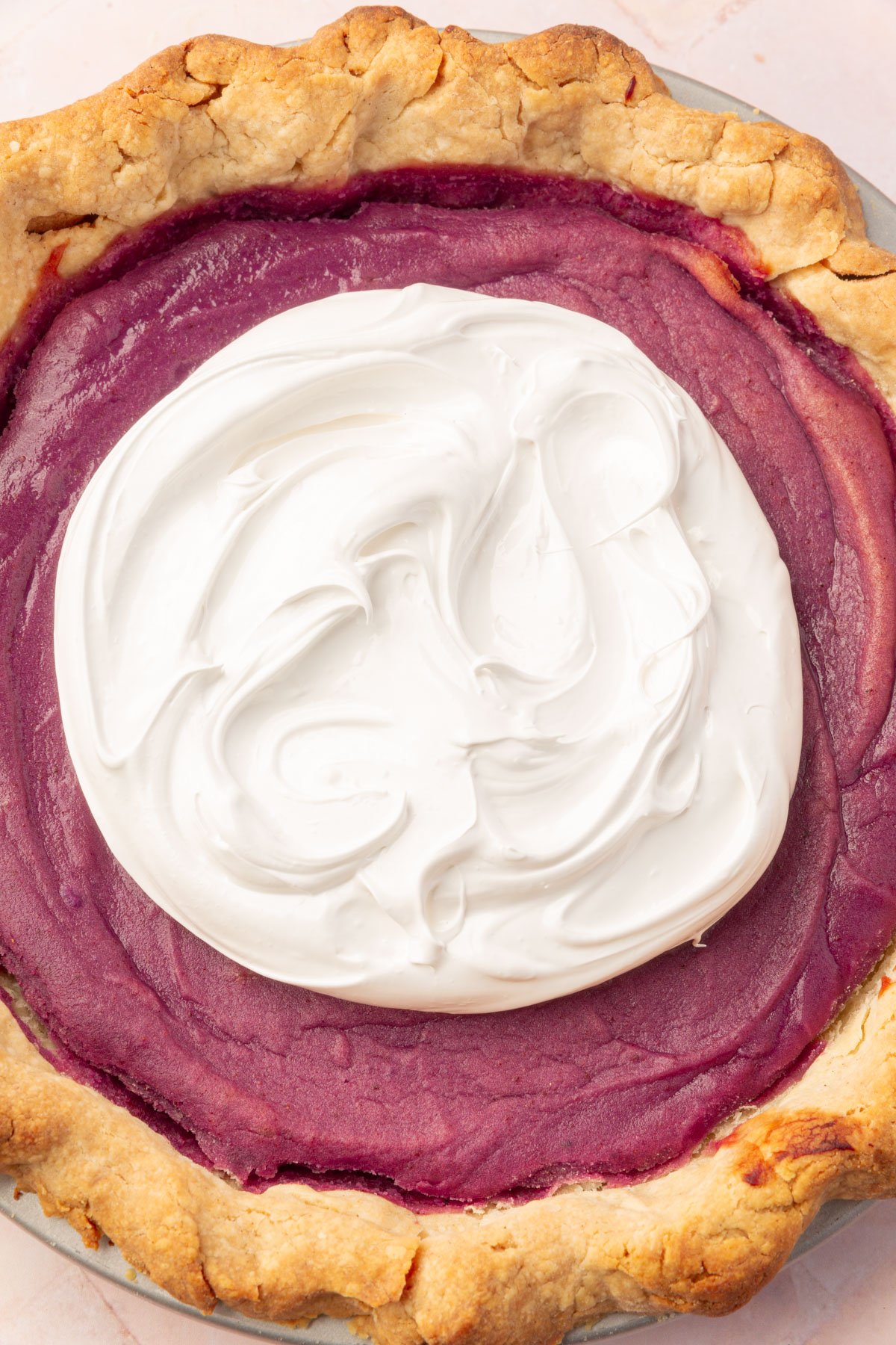 A gluten-free purple sweet potato pie topped with a large dollop of marshmallow meringue in the center.
