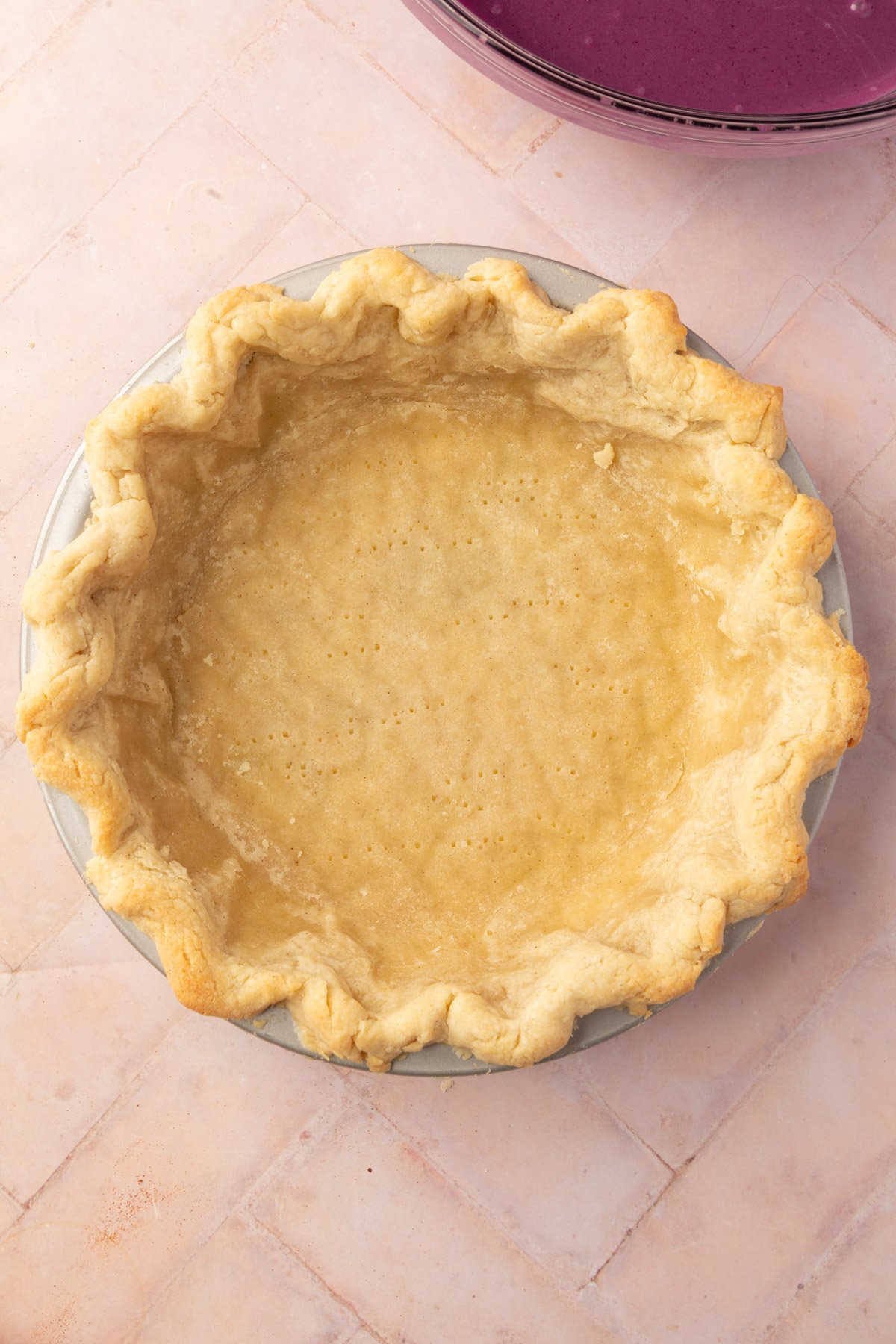 A prebaked gluten-free pie crust in a pie dish with fluted edges, prepared for the filling.