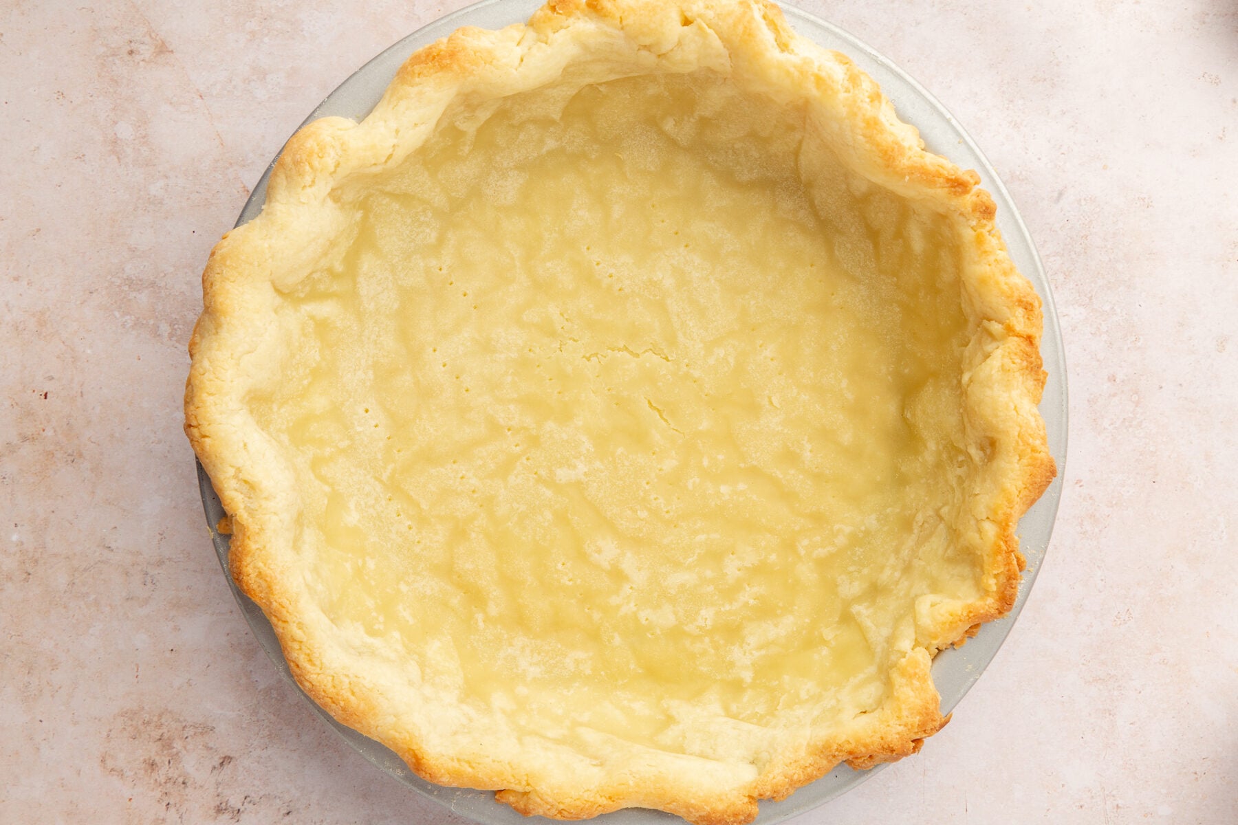 Image of gluten-free pie crush in a pie dish on a marble countertop.