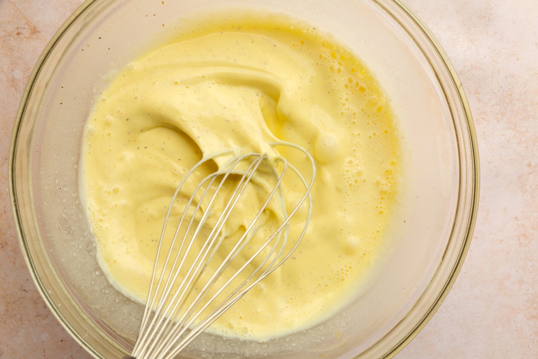 Image of heavy cream and milk whisked together in a clear mixing bowl.