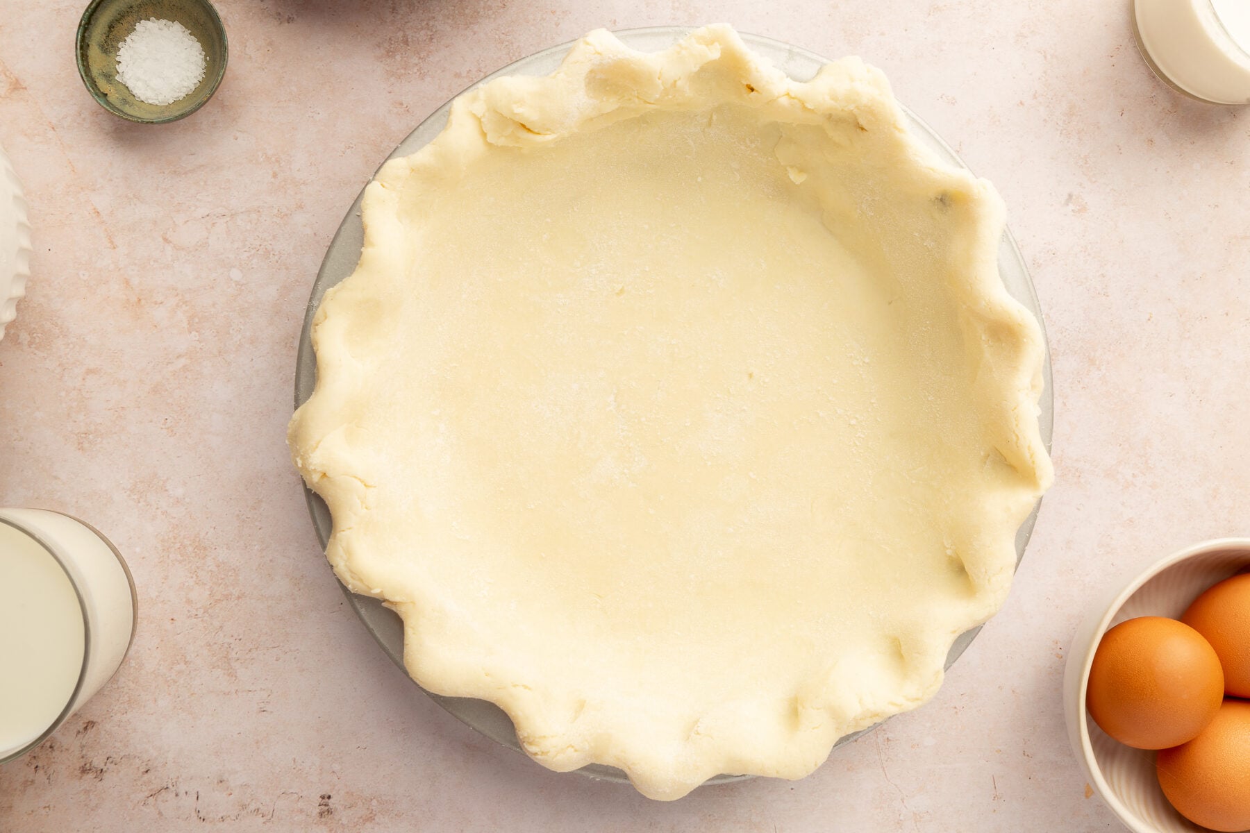 Uncooked gluten-free pie crust sitting in a pie dish sitting on a marble countertop.