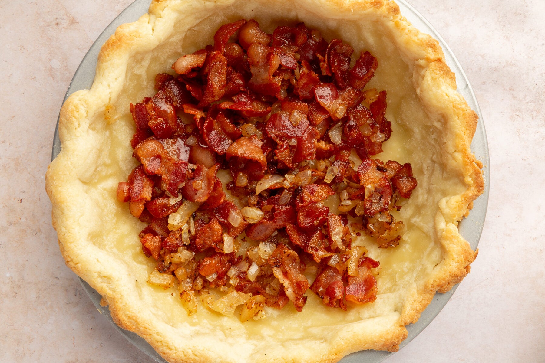 Image of gluten-free pie crust and cooked bacon in a pie dish.