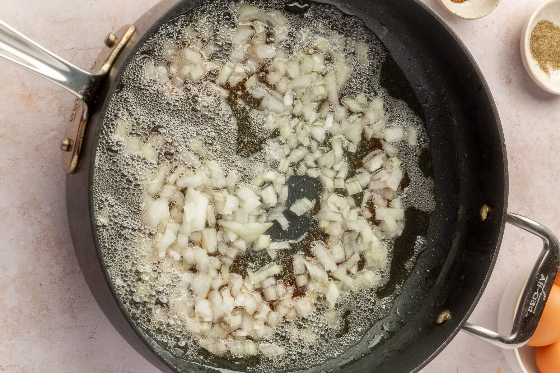 Chopped up onions, cooking in bacon fat in a large skillet.