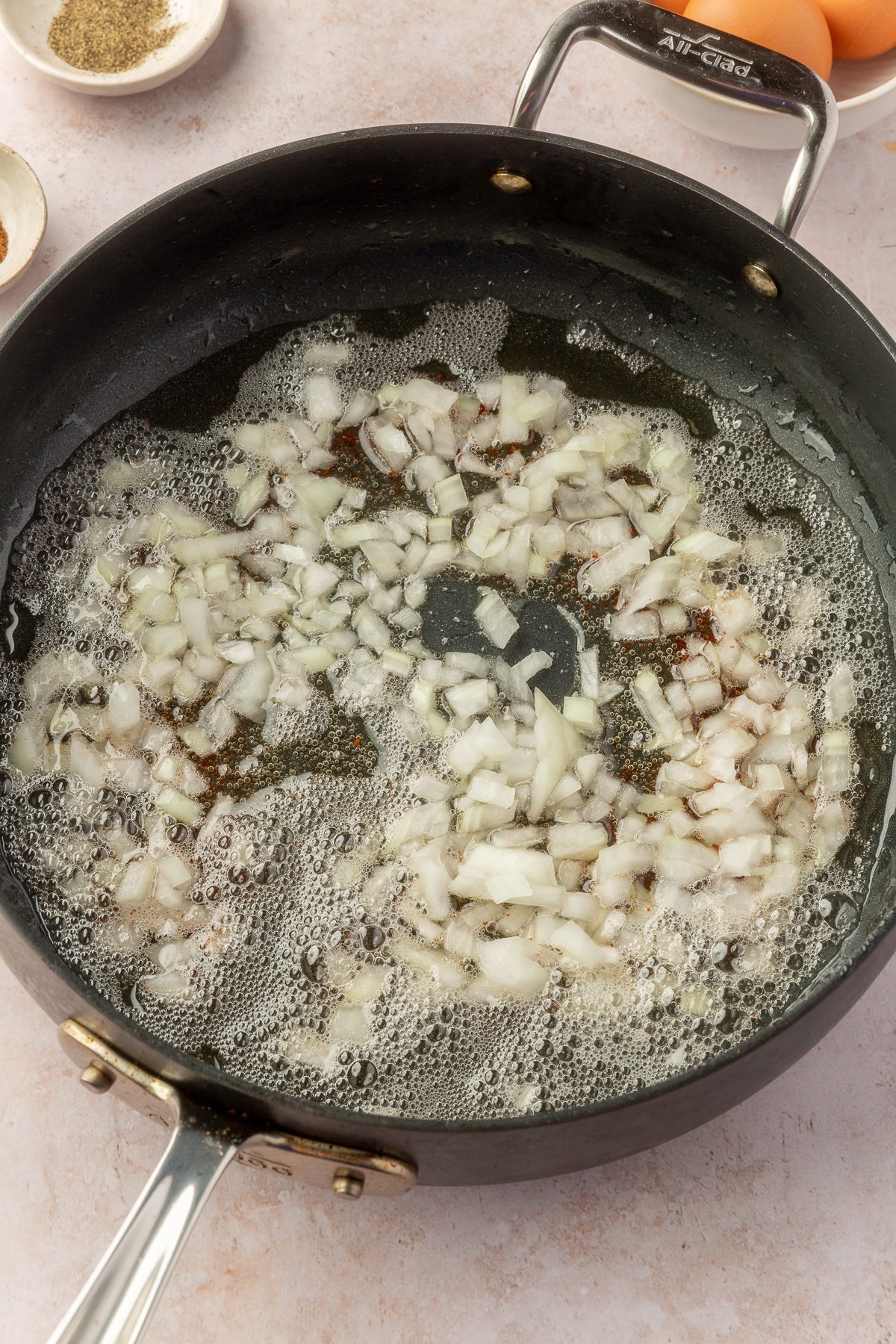 Chopped up onions, cooking in bacon fat in a large skillet.