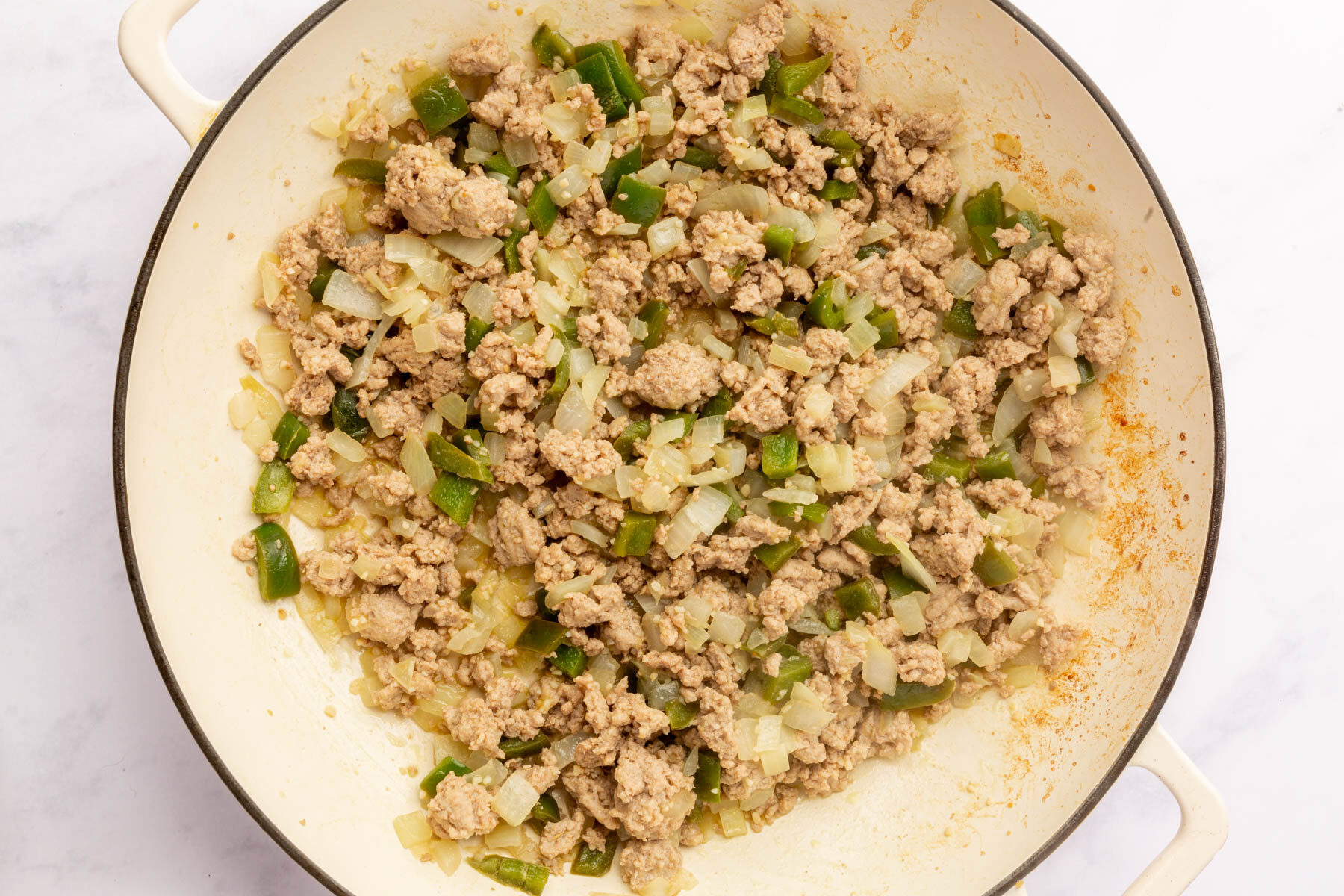Large mixing bowl filled with cooked ground turkey, yellow onion and green bell pepper.