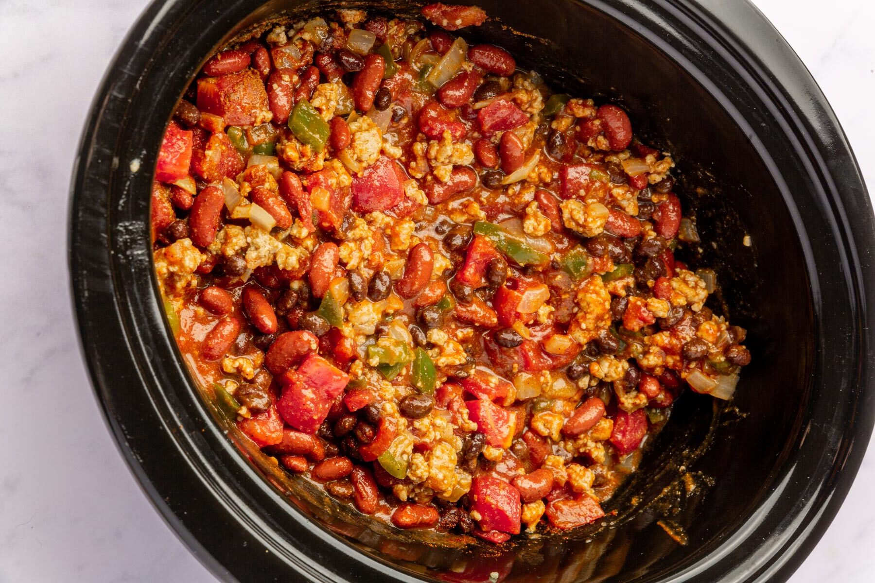 Crock pot filled with mixed ingredients for slow cooker turkey chili.