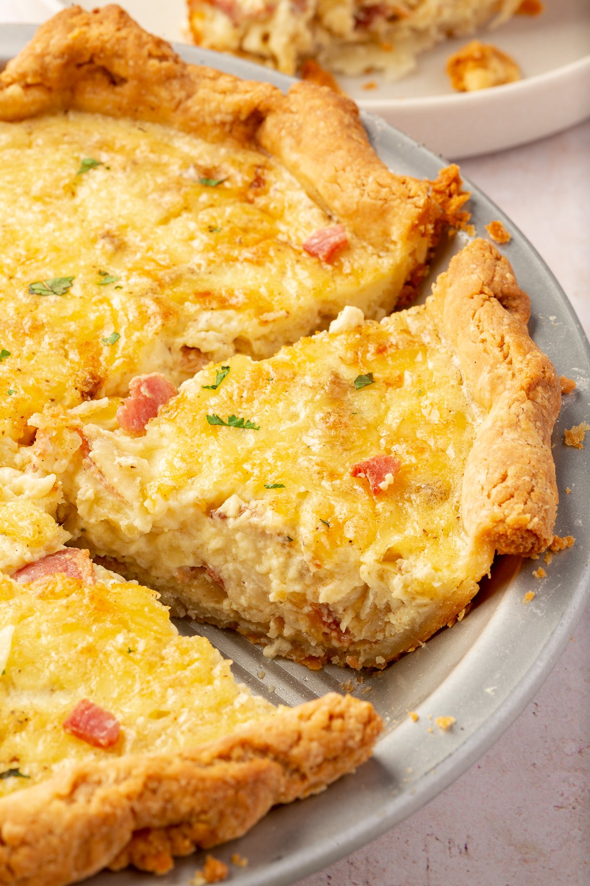 A partially sliced gluten free quiche in a metal pie tin.
