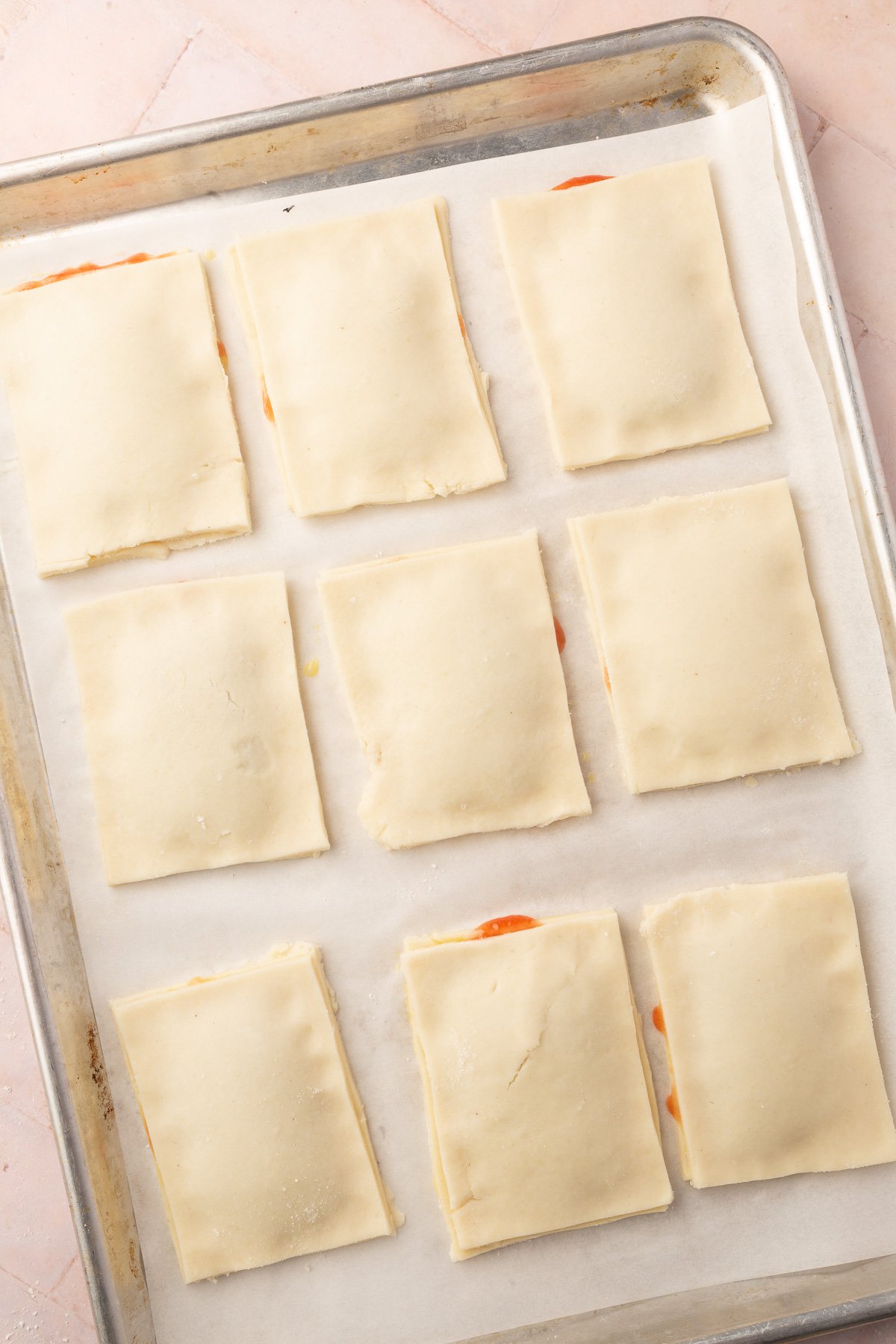 Uncooked pop tarts laying on baking sheet without holes poked in them.