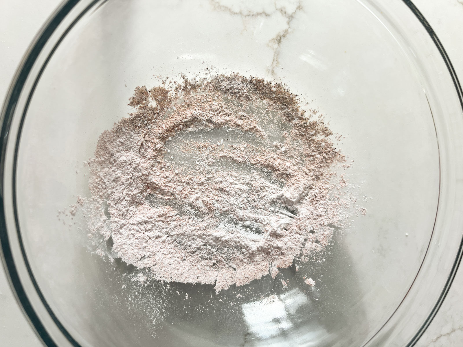 Baking powder and spices mixed together in a glass mixing bowl.