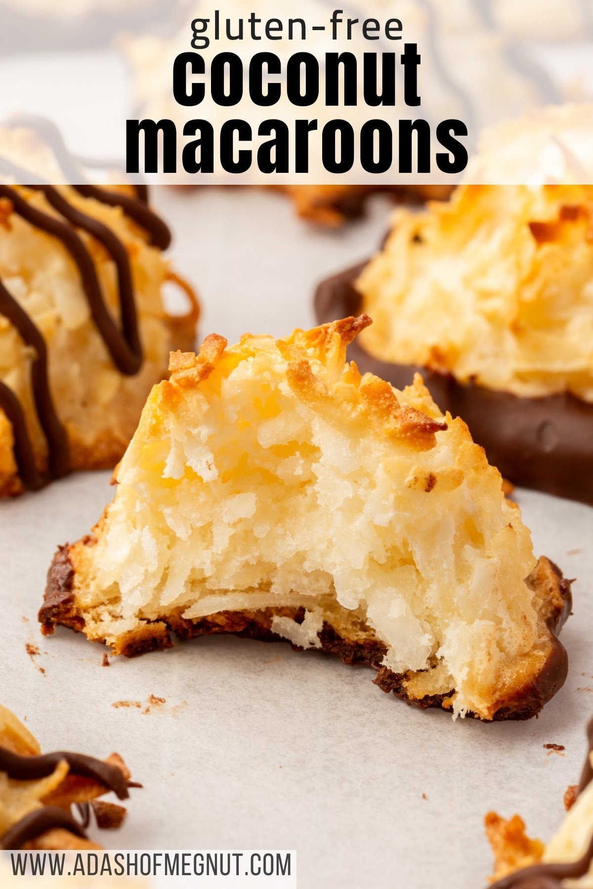 A bitten coconut macaroon revealing its moist, chewy interior, with chocolate on the bottom and other macaroons in the background.