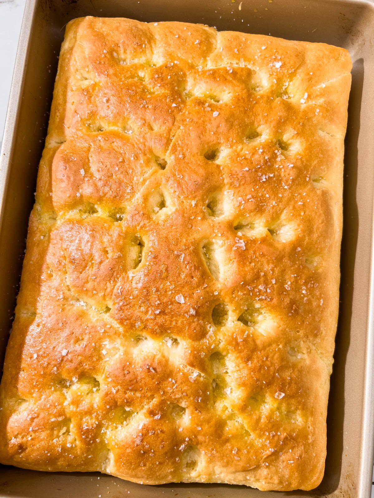 Golden brown gluten-free focaccia fresh from the oven, with a crisp crust and flaky sea salt on top.