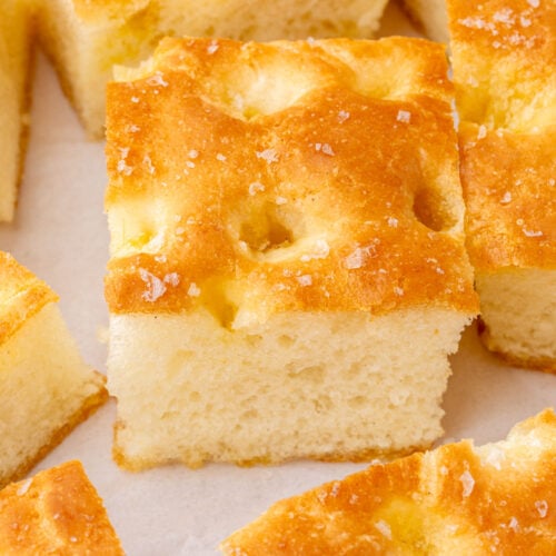 Extreme close-up of the dimpled top and open crumb structure of a slice of gluten-free focaccia with visible sea salt crystals.