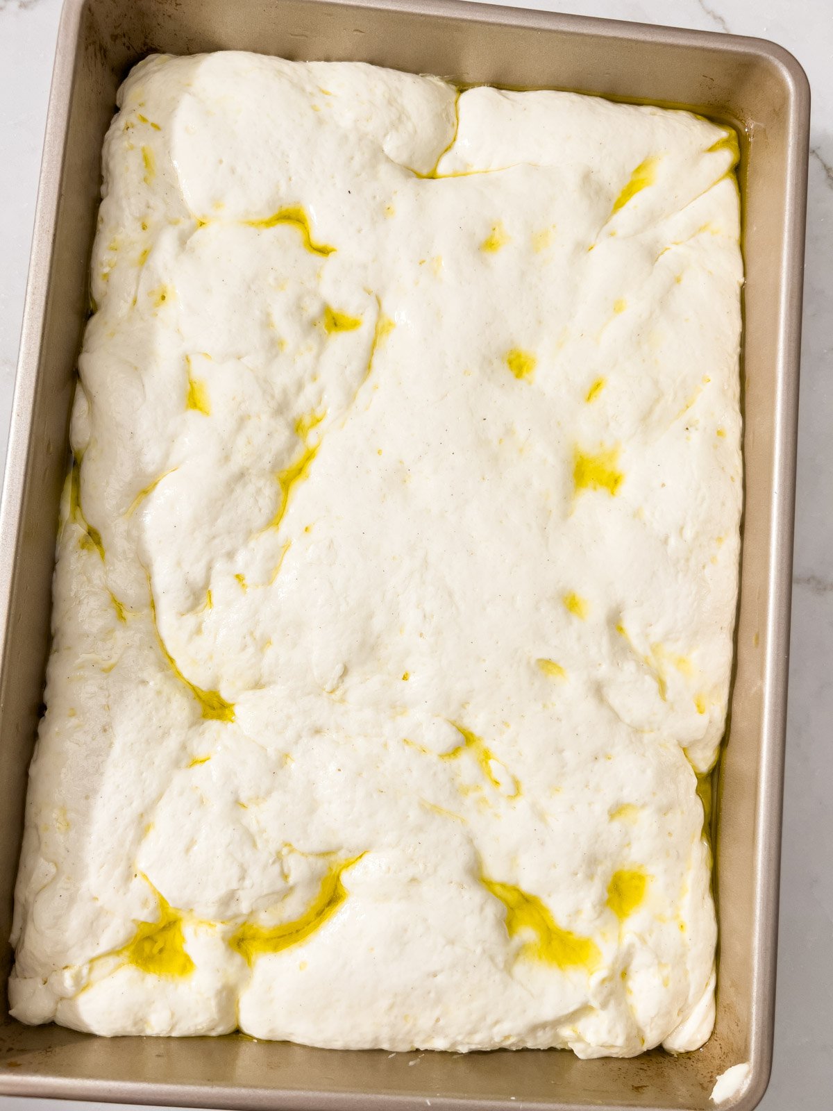 Fully risen focaccia dough in the pan, soft and airy.