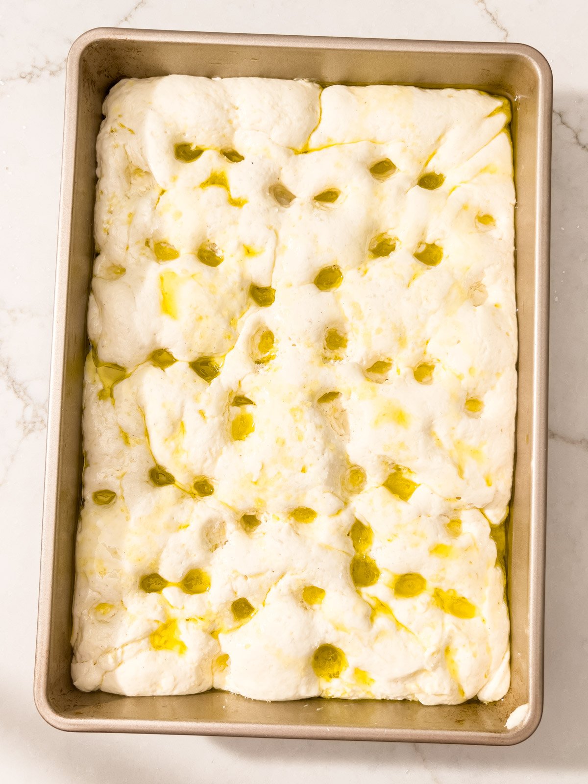 Risen dough dimpled with fingers and drizzled with olive oil just before baking.
