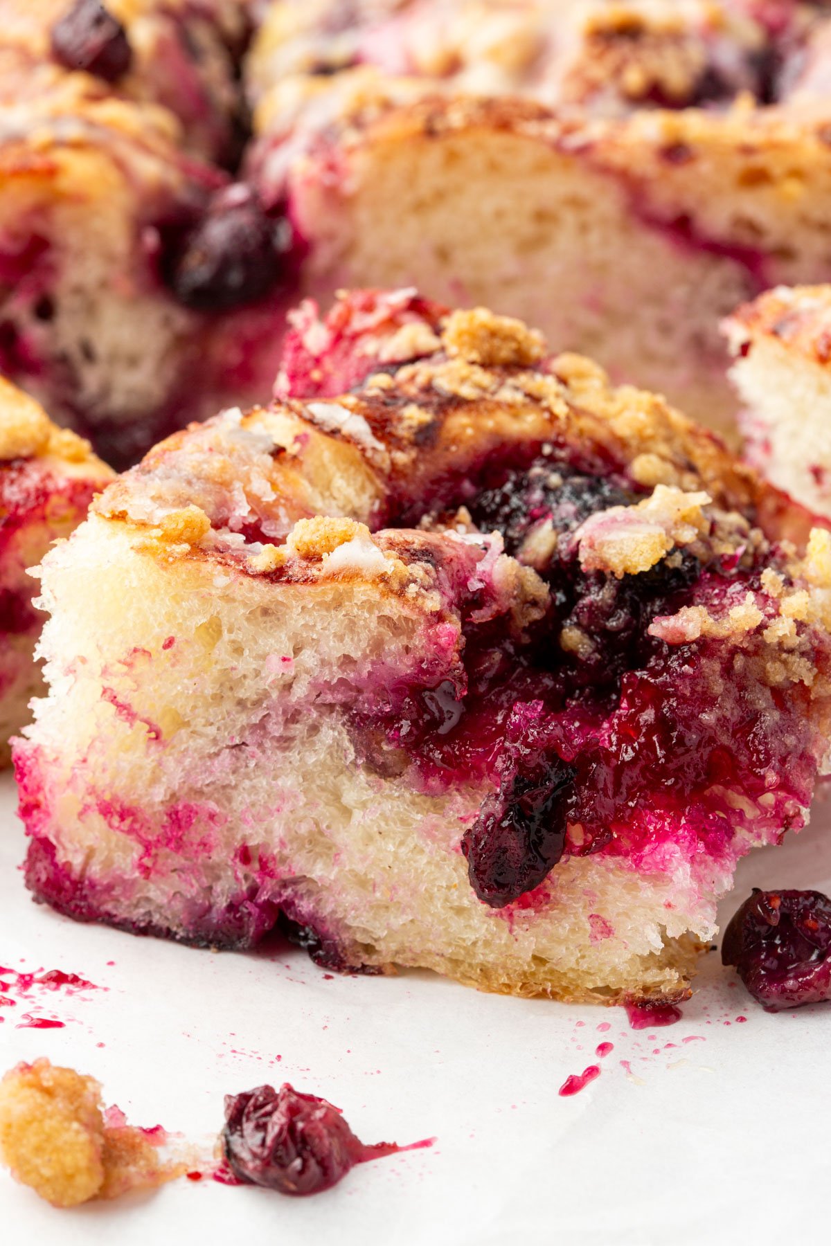 Close-up of a slice of gluten-free blueberry crumble focaccia showing airy crumb, vibrant blueberry compote, and golden crumble topping.