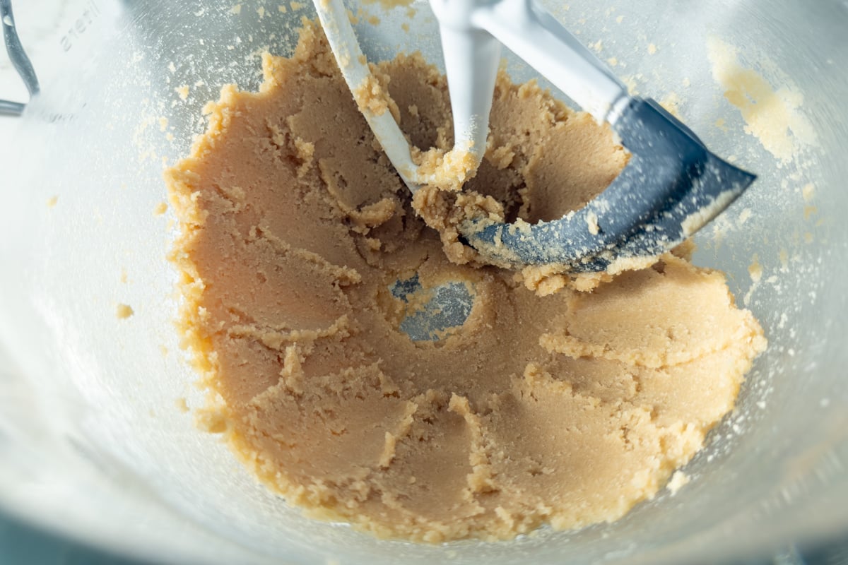 Creamed butter and sugar mixture in a stand mixer bowl with paddle attachment.