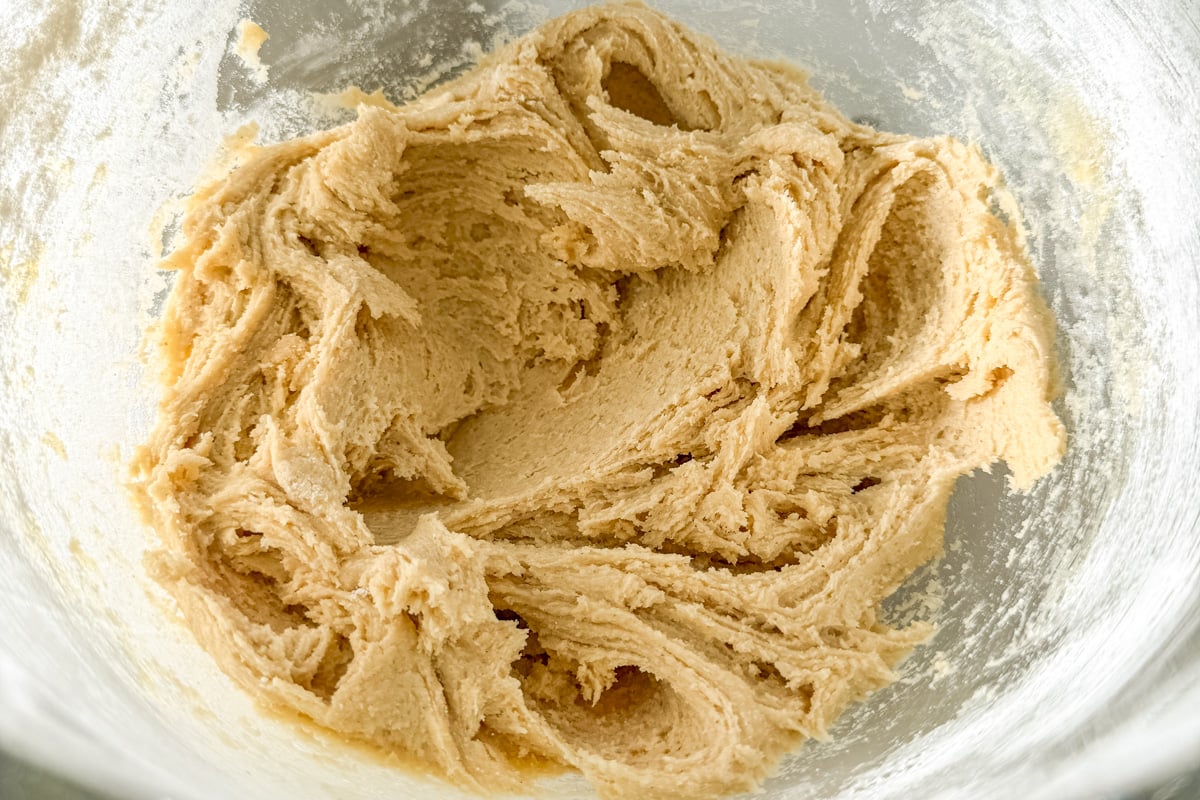 Mixed cookie dough in a glass bowl before shaping, with a light and fluffy texture.