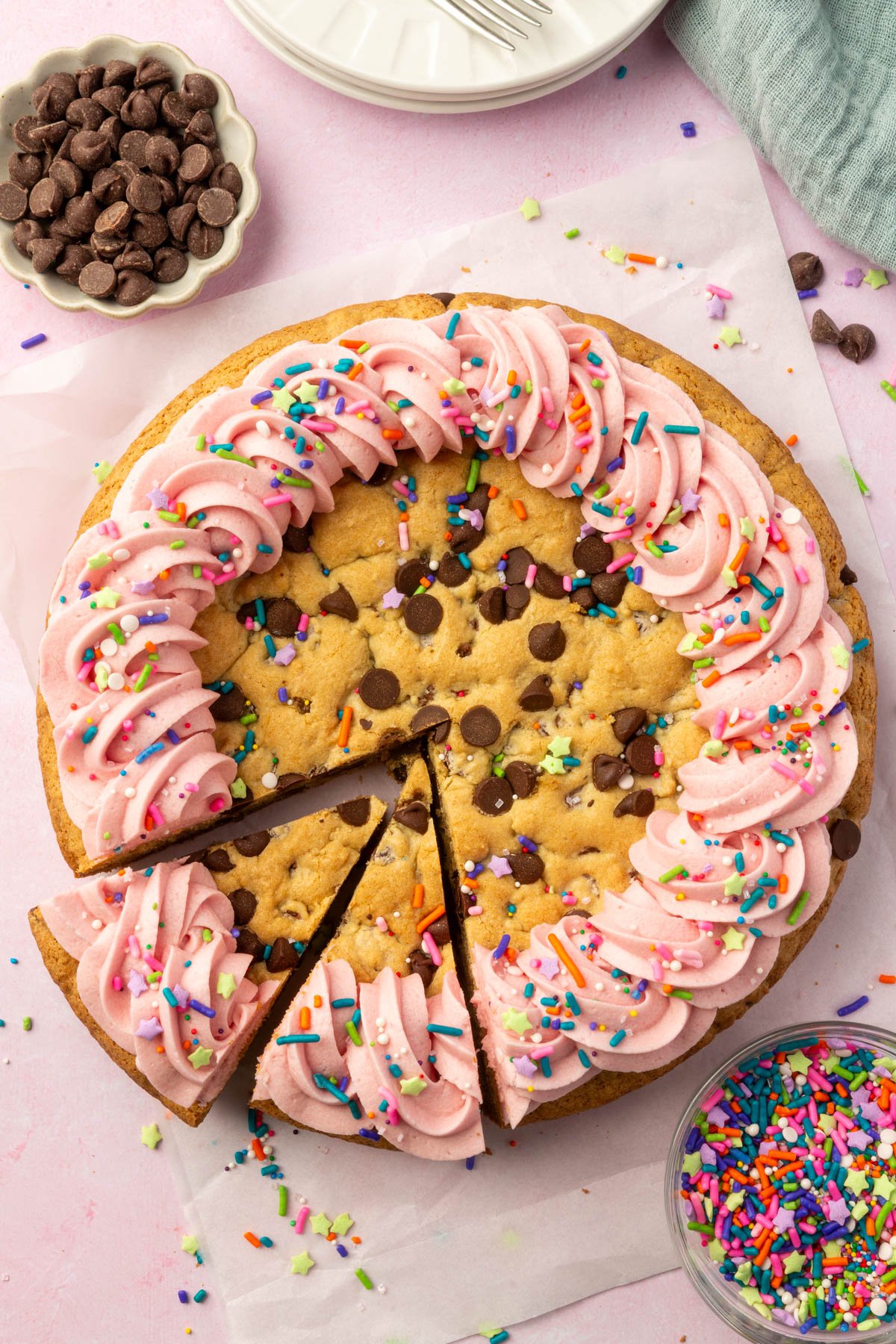 Top-down view of a gluten-free cookie cake with two slices cut and slightly pulled apart, revealing soft texture and decorated frosting.