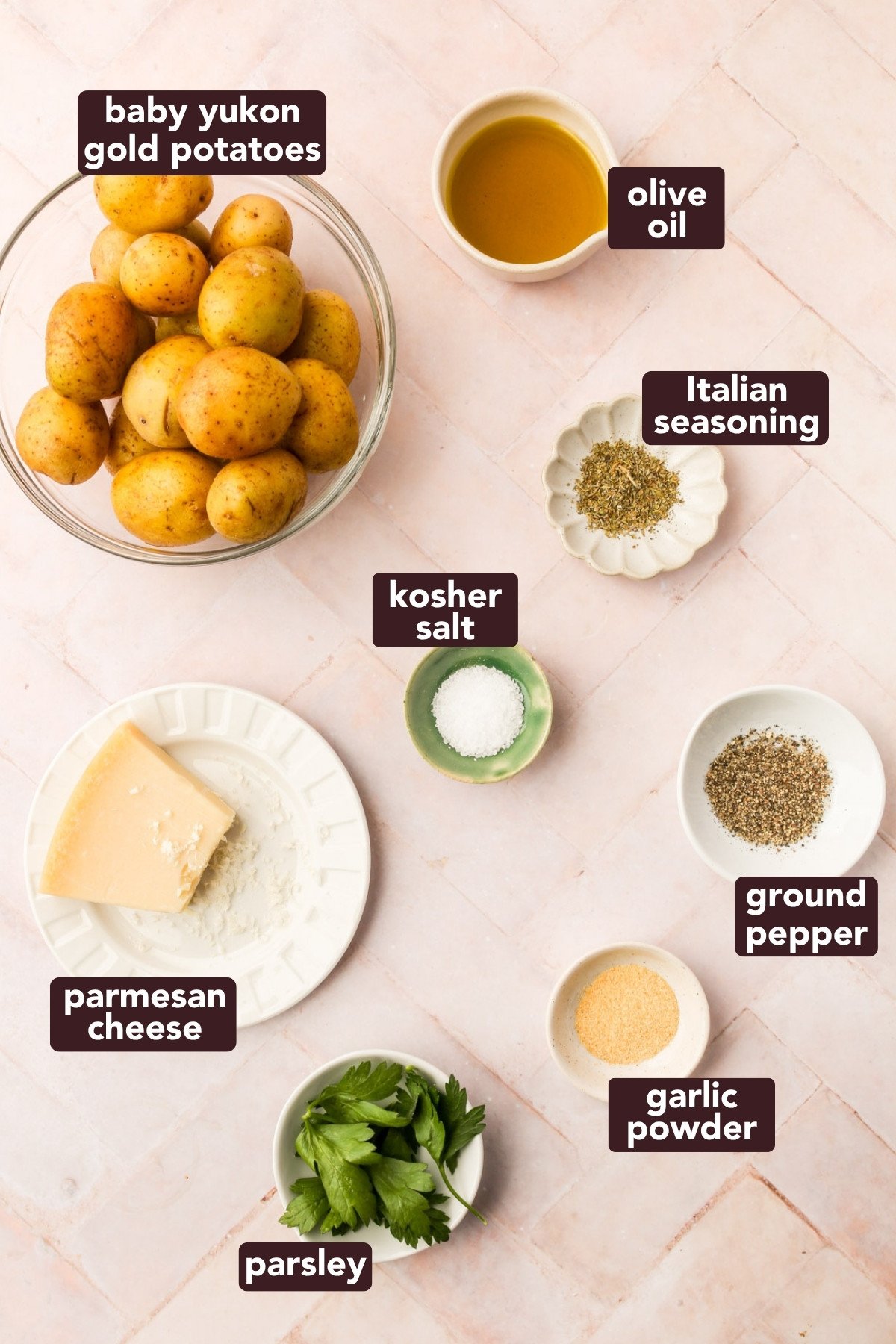 Overhead view of ingredients for crispy parmesan smashed potatoes, including baby Yukon golds, olive oil, spices, parsley, and Parmesan cheese.