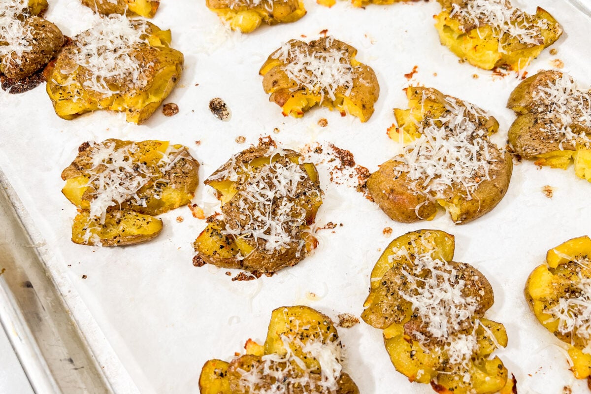 Golden smashed potatoes fresh from the oven with melted parmesan on top.