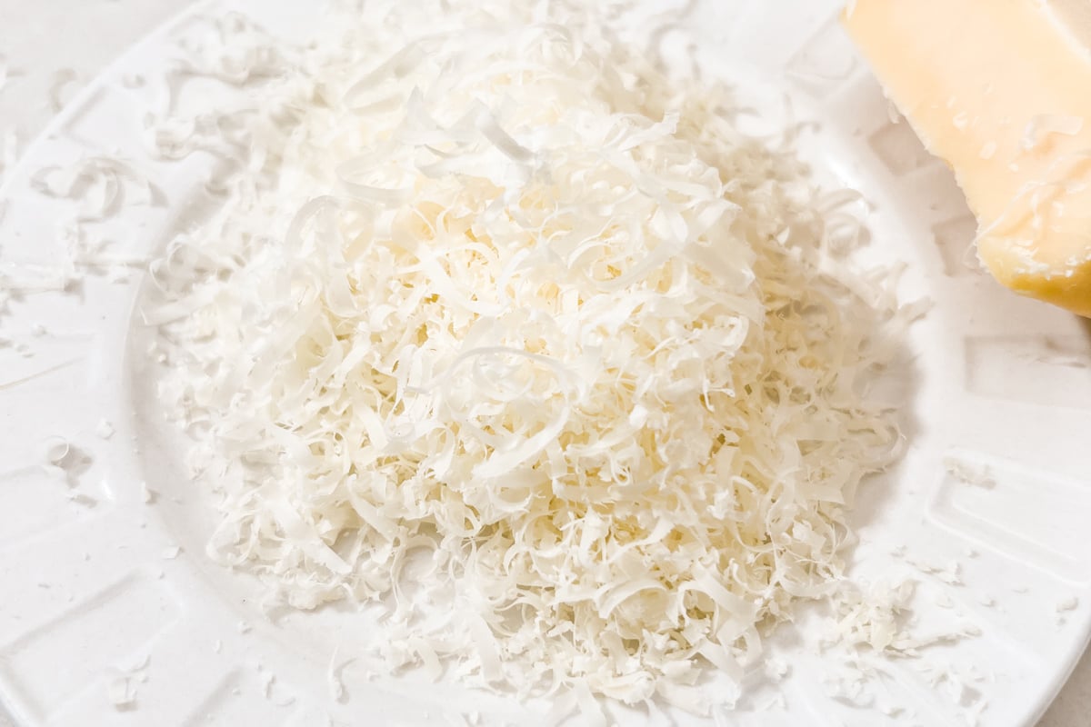 Microplaned parmesan cheese in a fluffy pile on a white plate.