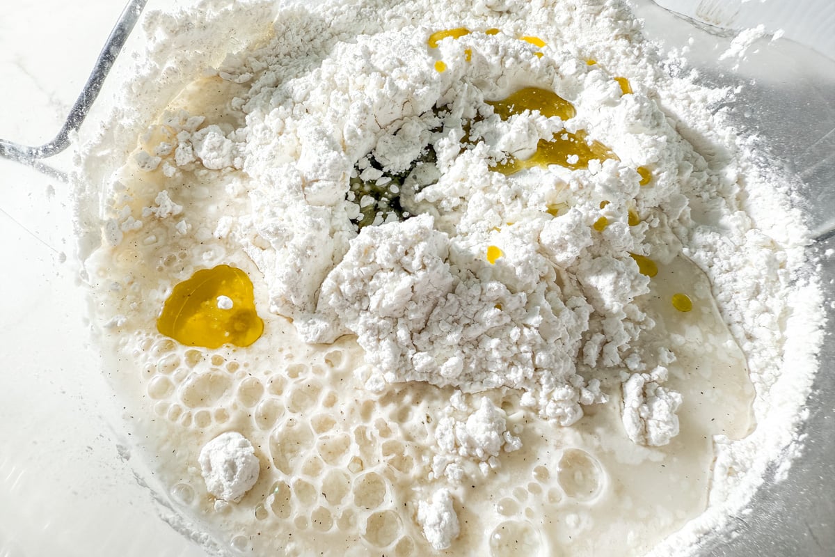 Caputo Fioreglut flour, warm water, yeast, and olive oil in a bowl before mixing for gluten-free focaccia dough.
