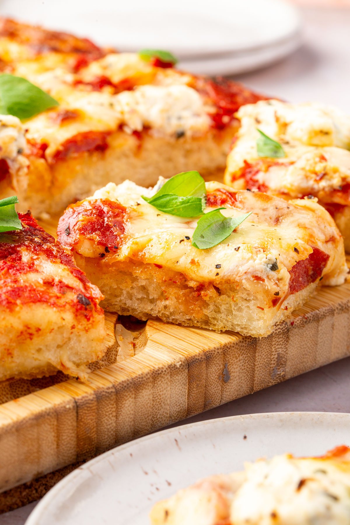 Side view of gluten-free focaccia pizza slices stacked to show thick crust and airy texture.