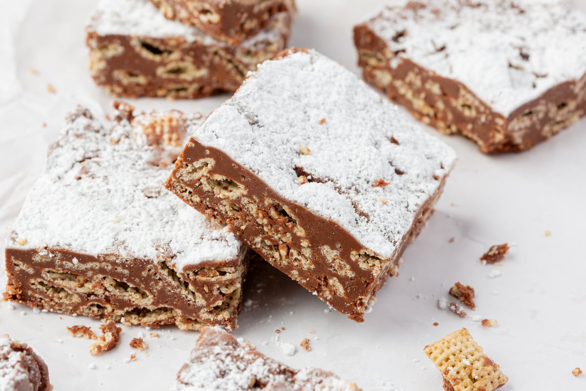 Sliced chocolate cereal bars arranged on parchment paper with crumbs around.