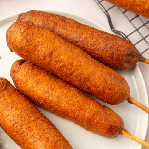 Golden-brown gluten-free corn dogs arranged on a white plate, ready to eat.
