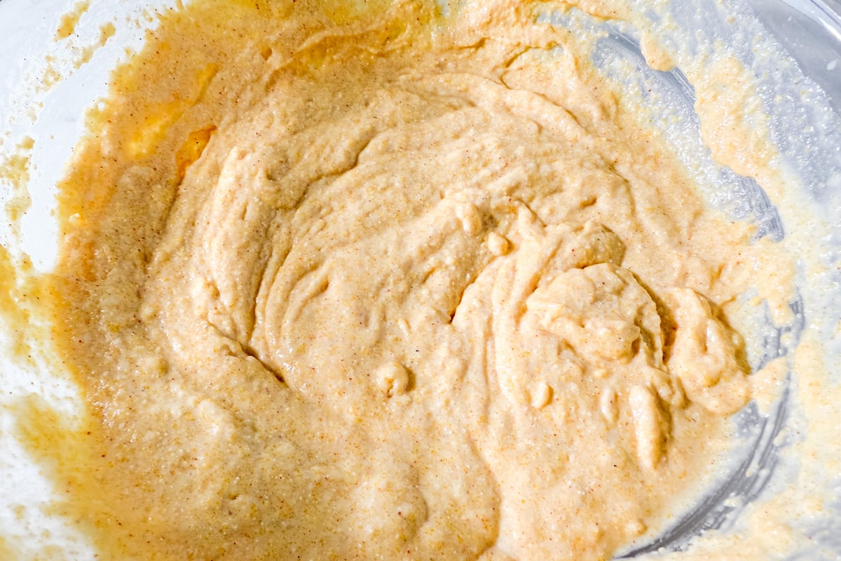 A bowl of smooth, golden gluten-free corn dog batter ready for dipping hot dogs.
