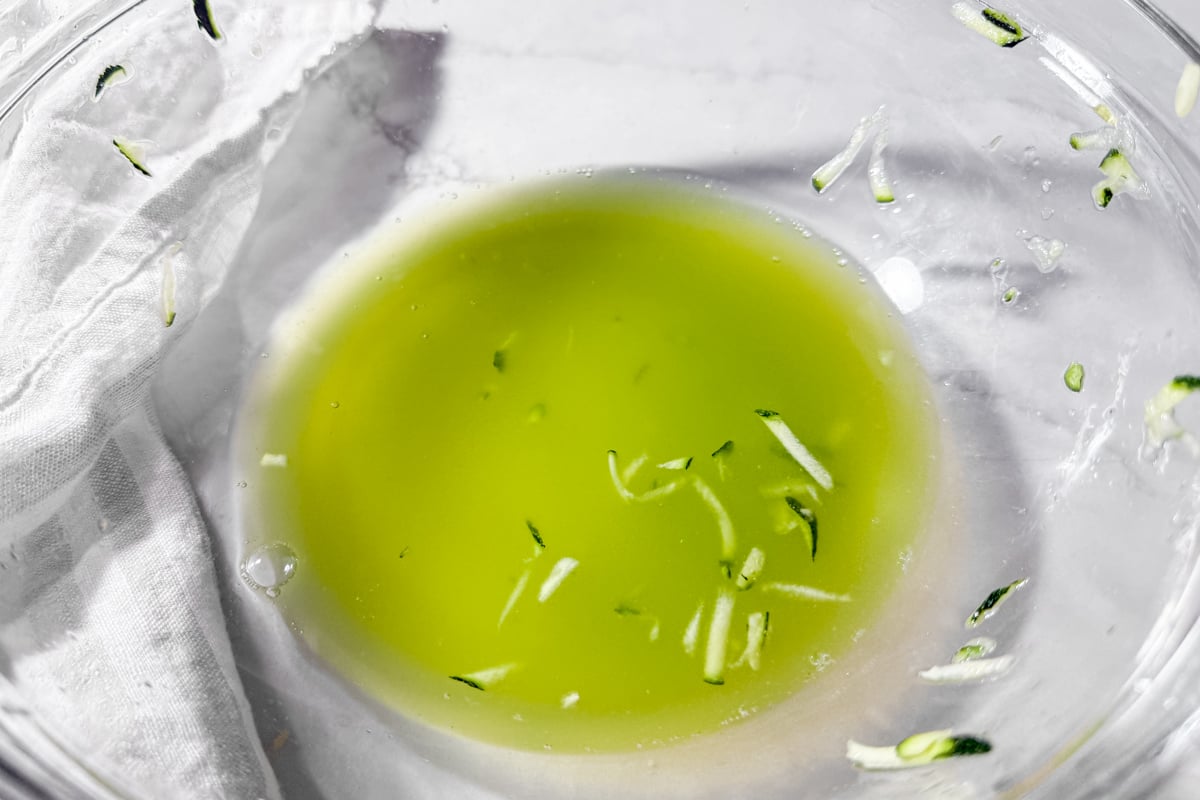 Bright green liquid left in the bowl after squeezing moisture from shredded zucchini.