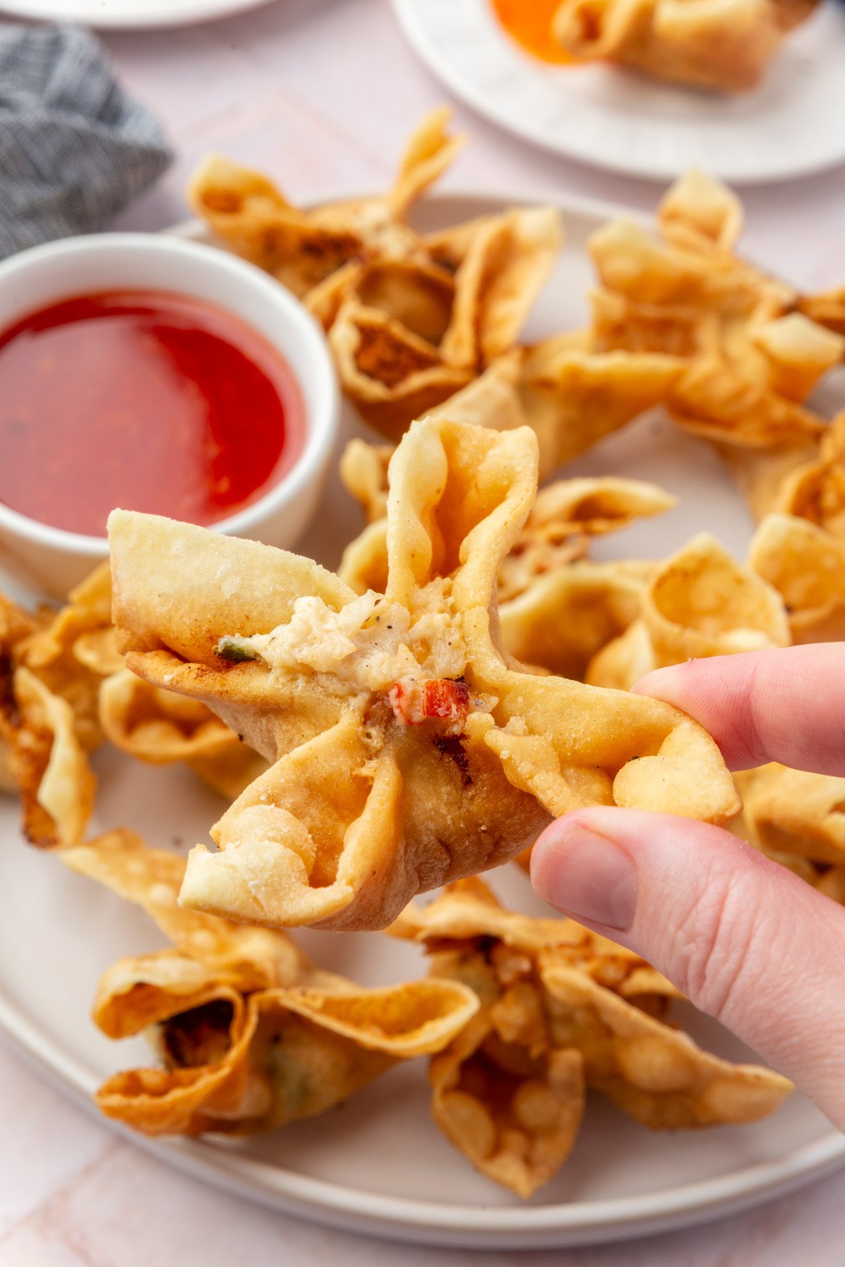 Close-up of gluten-free crab rangoons arranged on a serving plate with dipping sauce.