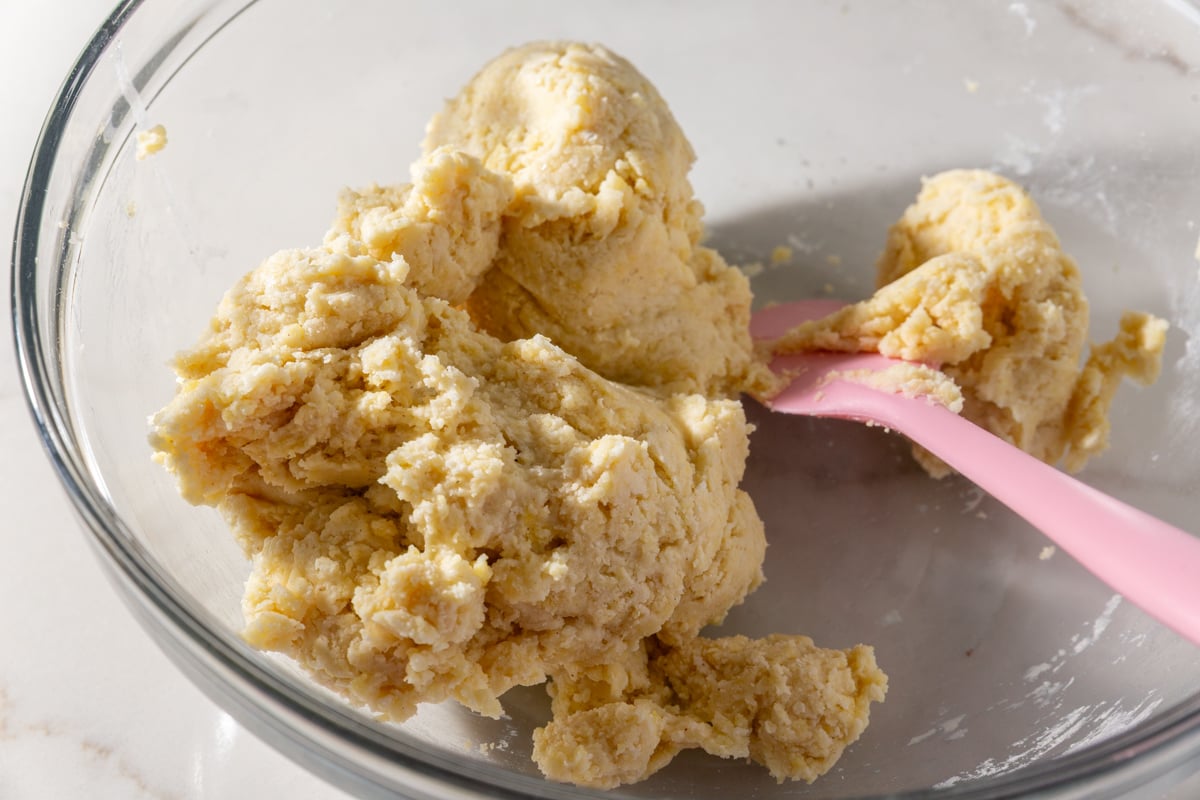 Smooth gluten-free wonton dough coming together in a glass bowl with a pink spatula.