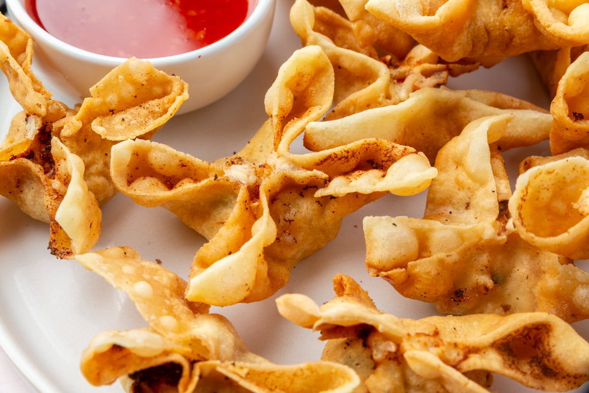 Close-up of golden, crispy gluten-free crab rangoons highlighting their bubbly, crunchy texture.