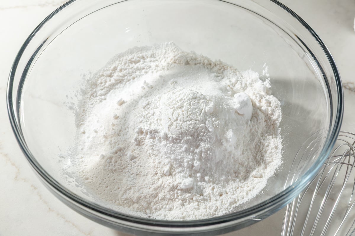 Glass bowl filled with gluten-free flour blend and dry ingredients before adding eggs and liquid.