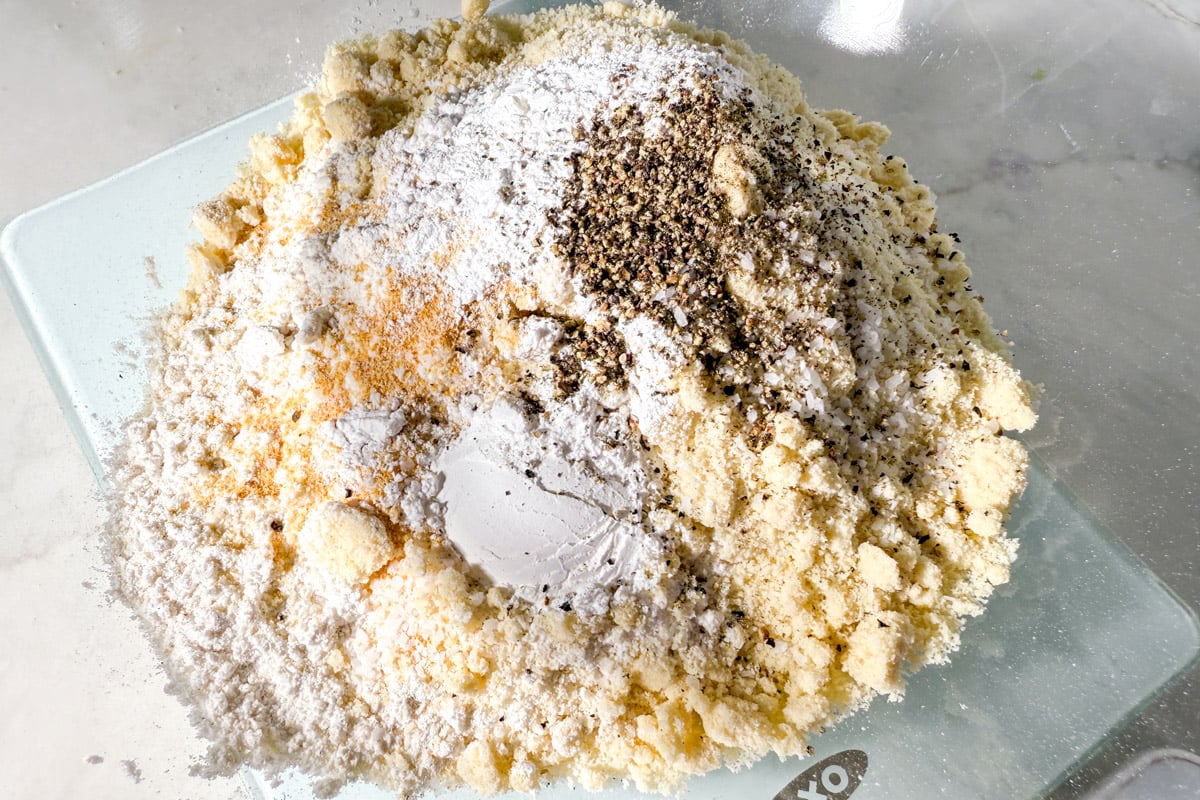 Gluten-free flour, almond flour, baking powder, salt, pepper, and seasonings piled in a mixing bowl.