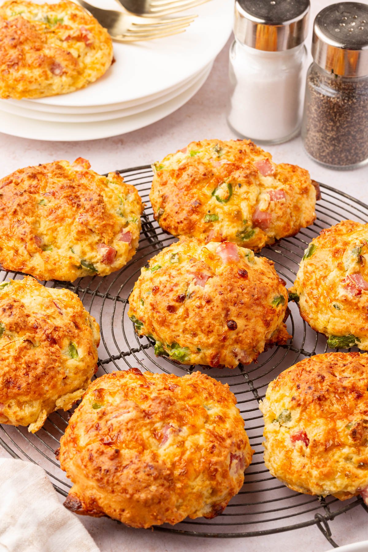 Golden brown gluten-free cottage cheese breakfast biscuits cooling on a wire rack with ham and green pepper pieces visible.