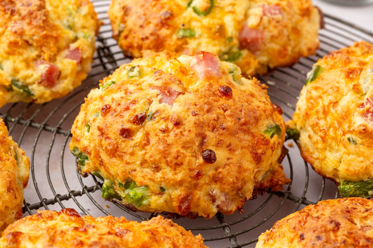 Close-up of a baked cottage cheese breakfast biscuit showing crispy edges, melted cheese, and chunks of ham and green pepper.