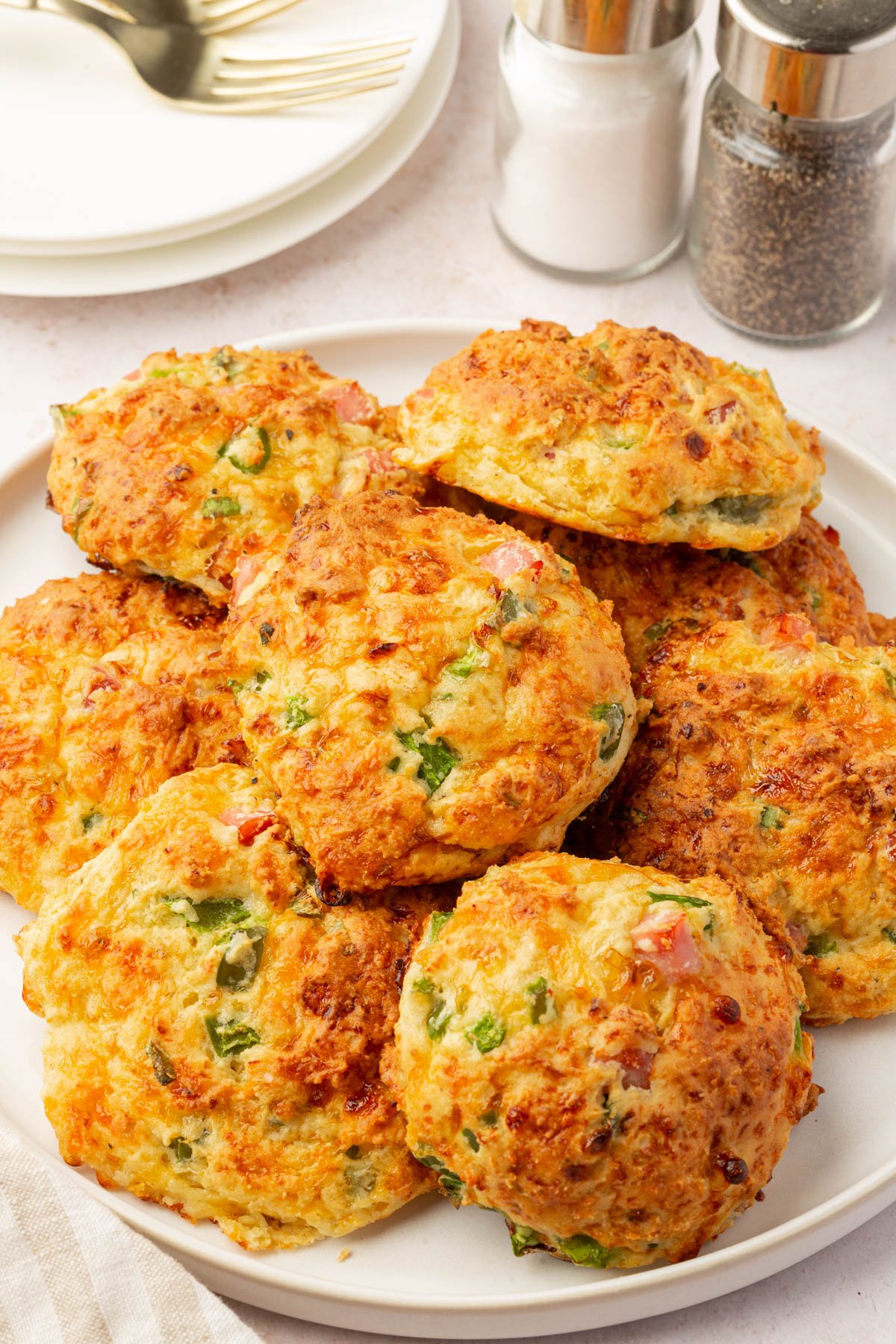Pile of gluten-free cottage cheese breakfast biscuits on a white plate with salt and pepper shakers in the background.
