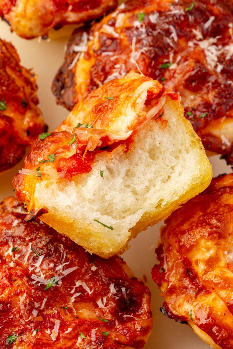 A gluten-free focaccia pizza muffin torn open to show the soft, airy interior with tomato sauce and melted cheese on top.