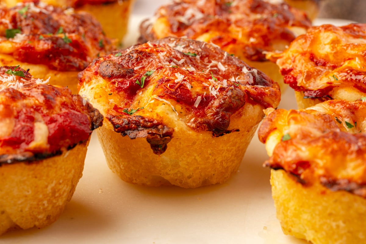 Close-up of baked gluten-free focaccia pizza muffins showing crisp cheese edges and golden texture.