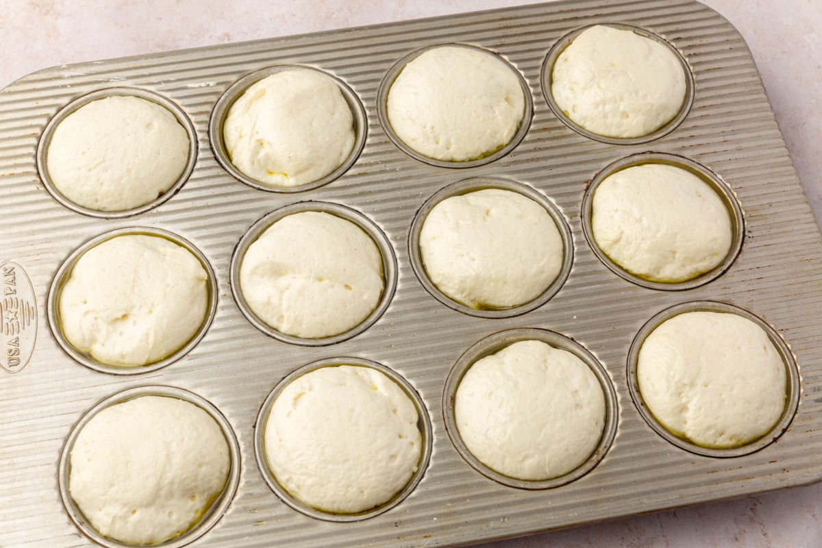 Risen gluten-free focaccia dough in muffin cups after proofing, ready to be topped.